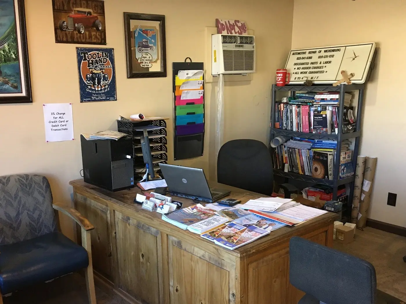 The front counter at Wickenburg Automotive Repair, with vintage garage signs, repair manuals and the shop's own promises posted on the wall