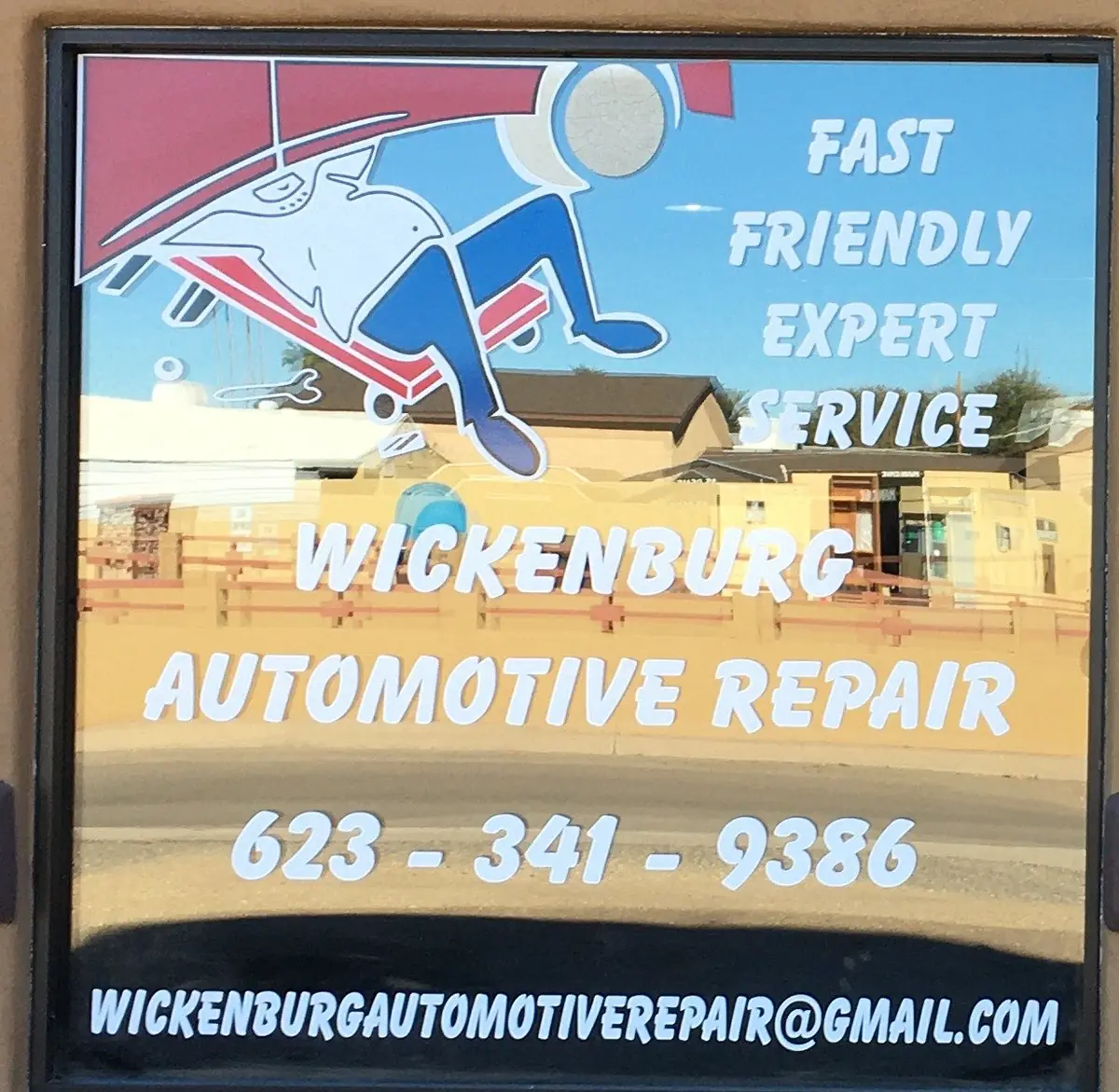 The hand-painted window sign at Wickenburg Automotive Repair, showing a mechanic on a creeper and the words Fast Friendly Expert Service
